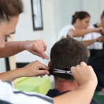 Student girl in hairdressing learning how to cut hair